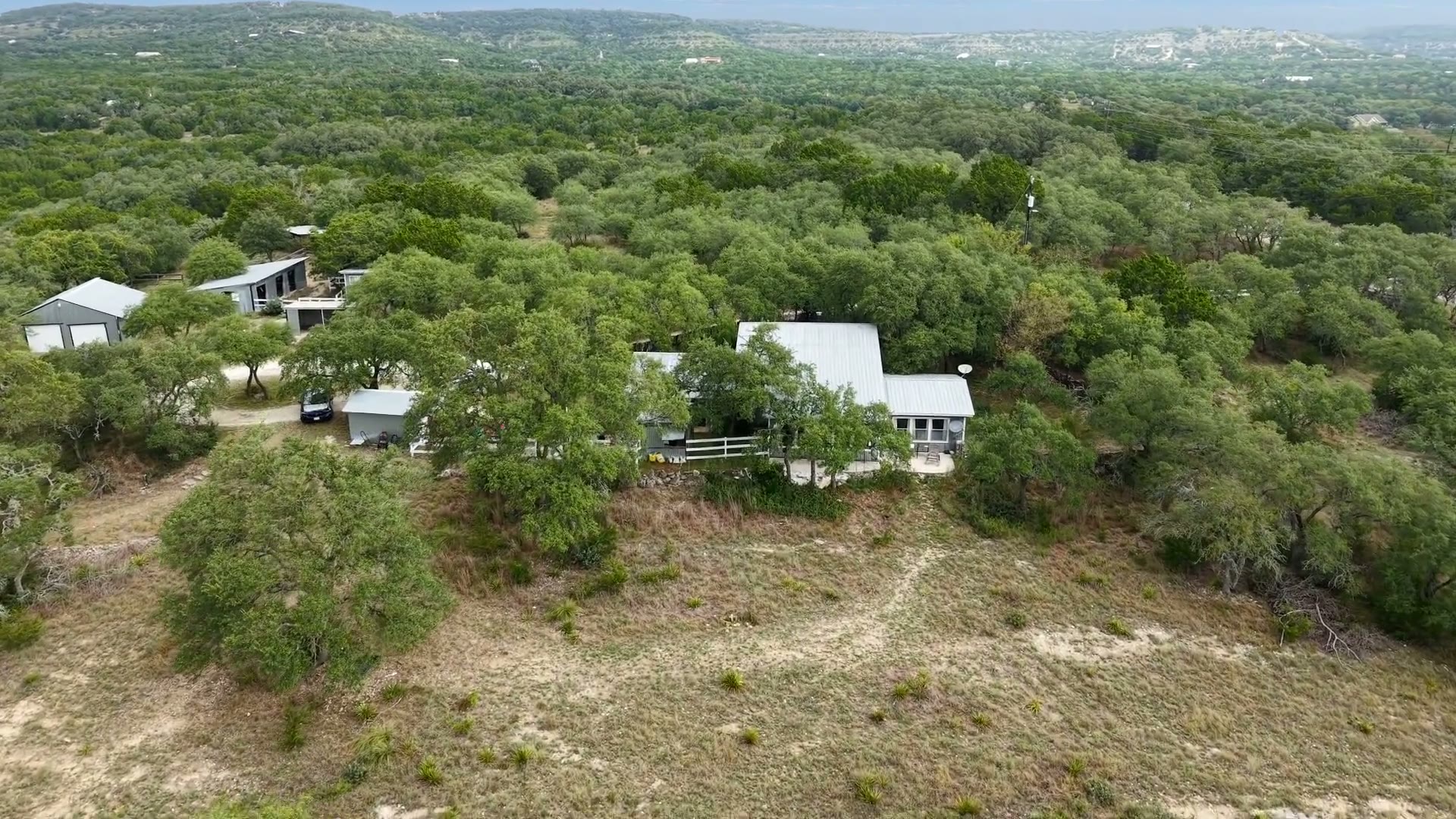Aerial view of Starry Hilltop surrounded by the wooded hills of Wimberley, Texas.