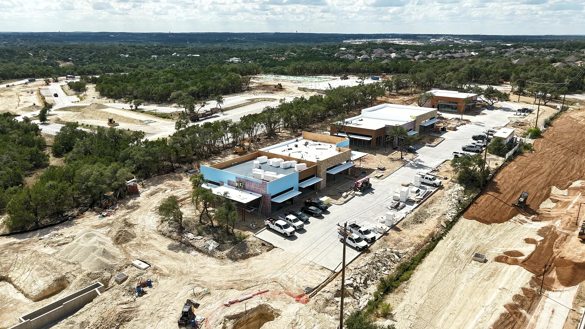 Aerial view of an active Austin construction site with commercial buildings, earthwork, and road access.